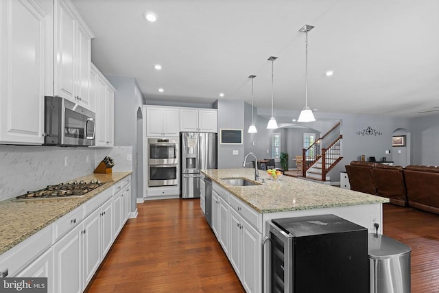  - kitchen featuring stainless steel appliances, arched walkways, open floor plan, dark wood-style flooring, and tasteful backsplash