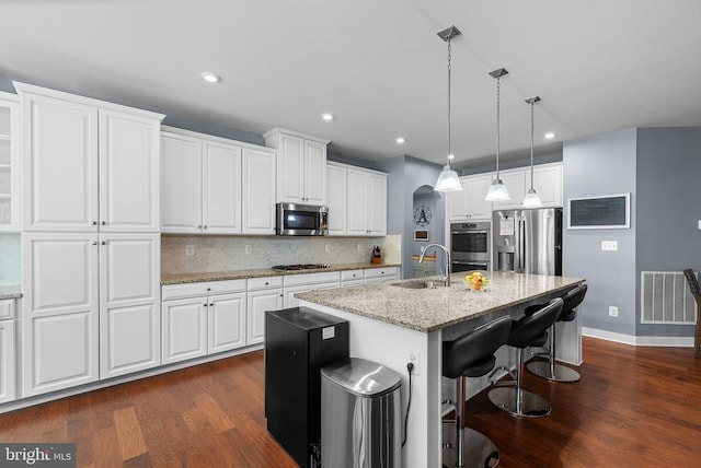  - kitchen with stainless steel appliances, dark wood-style floors, white cabinetry, a center island with sink, and recessed lighting