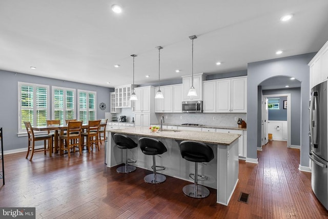  - kitchen with stainless steel appliances, arched walkways, white cabinets, decorative backsplash, and recessed lighting
