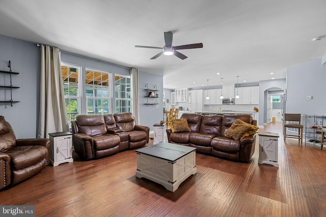  - living area featuring ceiling fan, dark wood-style flooring, arched walkways, and healthy amount of natural light