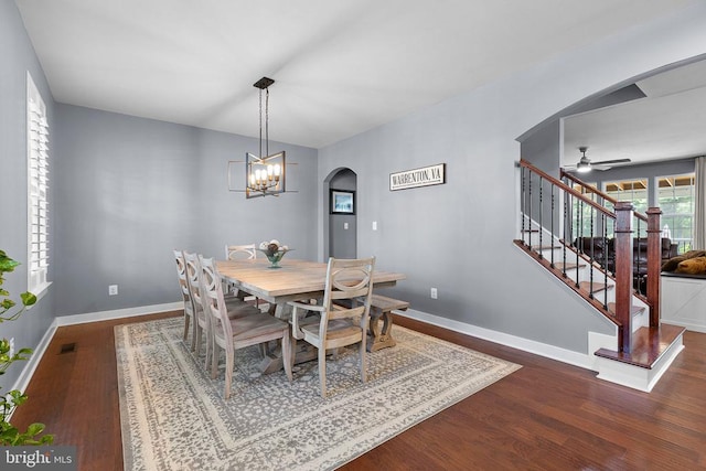  - dining room with arched walkways, wood finished floors, stairway, a ceiling fan, and a chandelier
