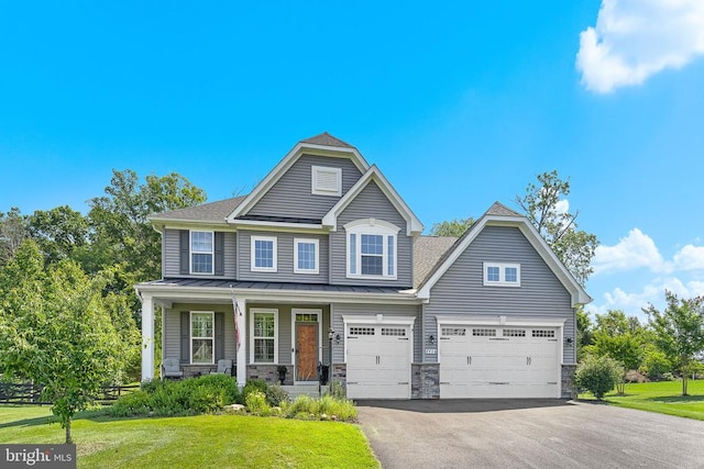  - view of front of house featuring a standing seam roof, asphalt driveway, a front lawn, stone siding, and a metal roof
