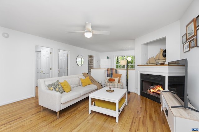 11 Holly Cir, Palmyra, VA 22963 - living room featuring a warm lit fireplace, ceiling fan, light wood-style floors, and baseboards
