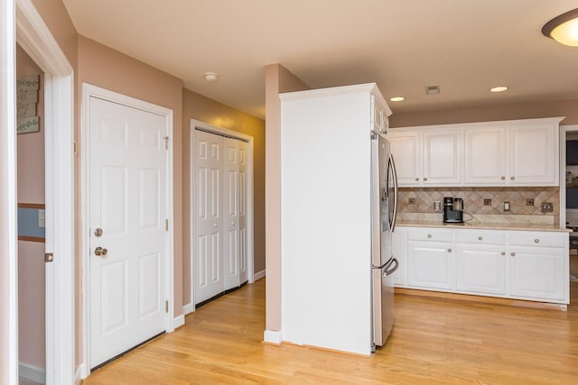 kitchen featuring freestanding refrigerator, light countertops, white cabinets, light wood-style flooring, and recessed lighting