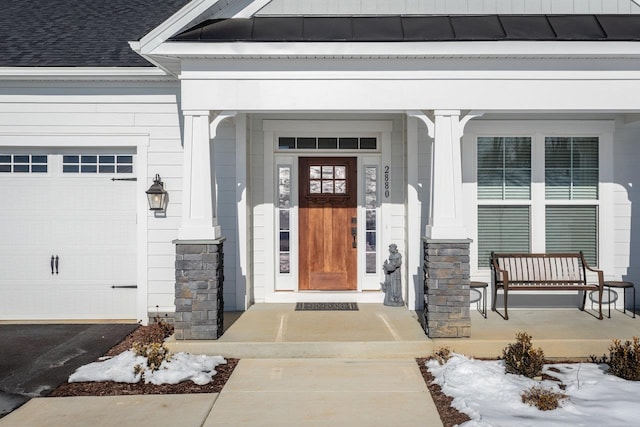 view of exterior entry with a garage and covered porch