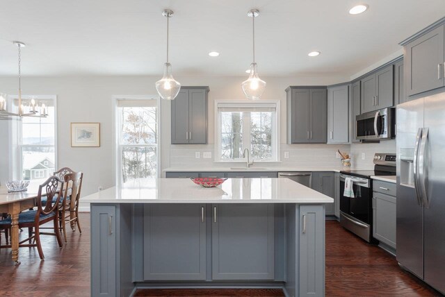 kitchen with gray cabinetry, sink, decorative light fixtures, and stainless steel appliances