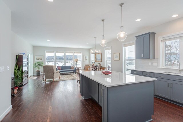 kitchen featuring a kitchen island, decorative light fixtures, sink, gray cabinetry, and dark hardwood / wood-style flooring