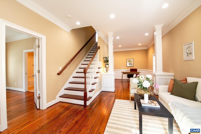 living room featuring stairway, crown molding, decorative columns, and hardwood / wood-style flooring