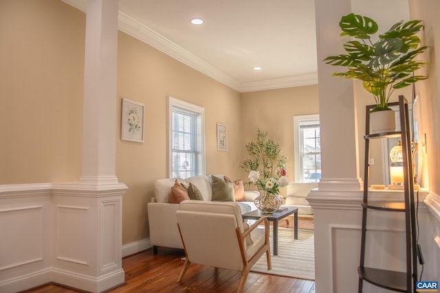 living area featuring ornamental molding, wood-type flooring, ornate columns, and recessed lighting