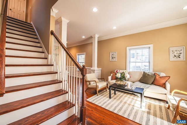 living area featuring a healthy amount of sunlight, crown molding, decorative columns, and wood finished floors