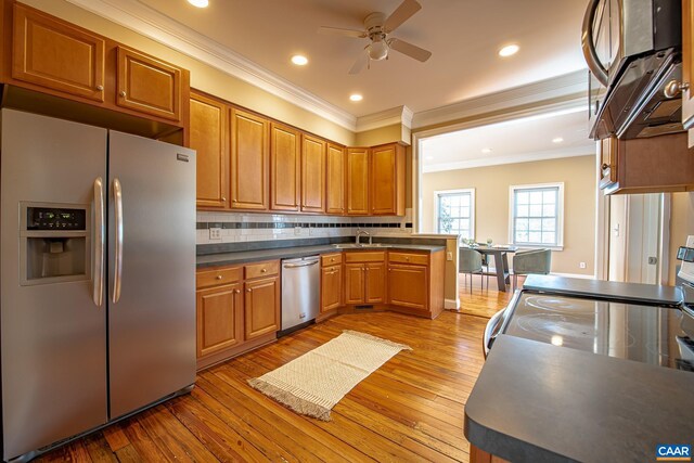 kitchen with a sink, stainless steel appliances, hardwood / wood-style floors, crown molding, and ceiling fan