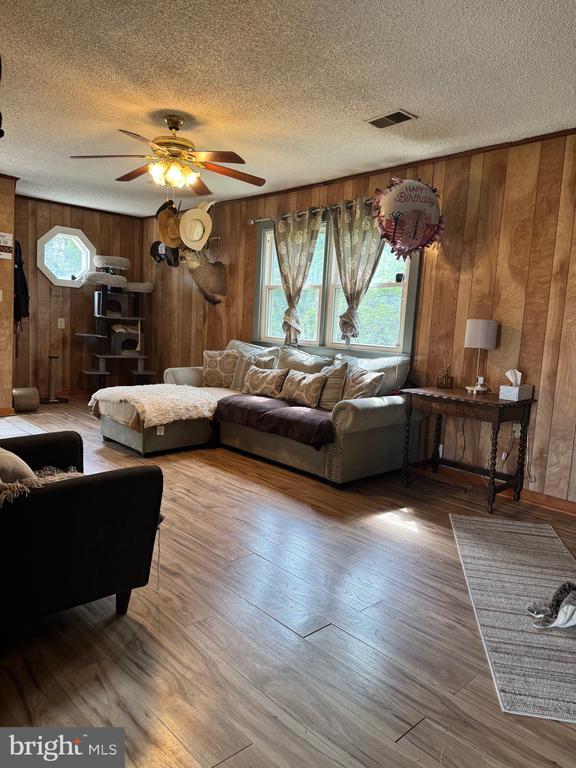 633 Ridge View Ln, Shenandoah, VA 22849 - living room featuring wooden walls, a textured ceiling, ceiling fan, and wood finished floors