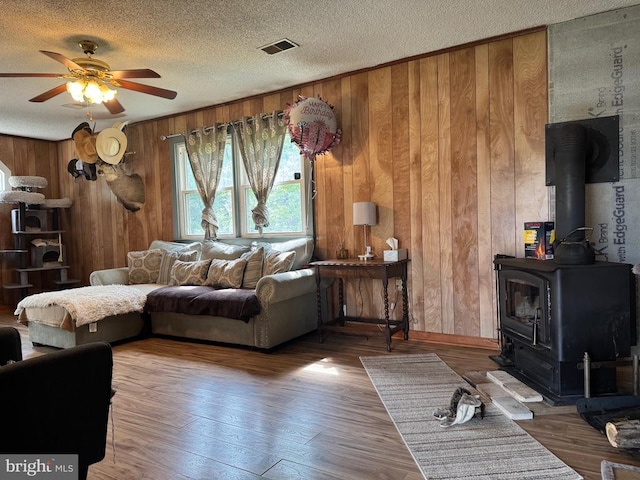633 Ridge View Ln, Shenandoah, VA 22849 - living room featuring ceiling fan, a wood stove, wood finished floors, wooden walls, and a textured ceiling