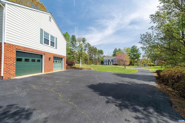 3340 Meadowfield Ln, Charlottesville, VA 22911 - view of side of home with asphalt driveway, brick siding, an attached garage, and a yard