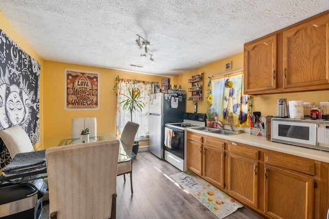 kitchen featuring sink, white appliances, a textured ceiling, and wood-type flooring