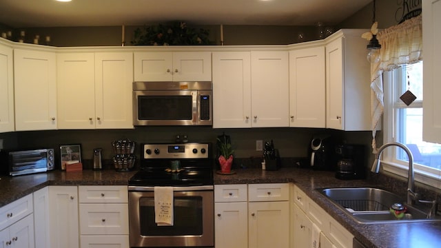 kitchen featuring appliances with stainless steel finishes, white cabinets, and a sink