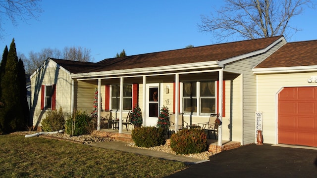 ranch-style home with a garage, a porch, and a shingled roof