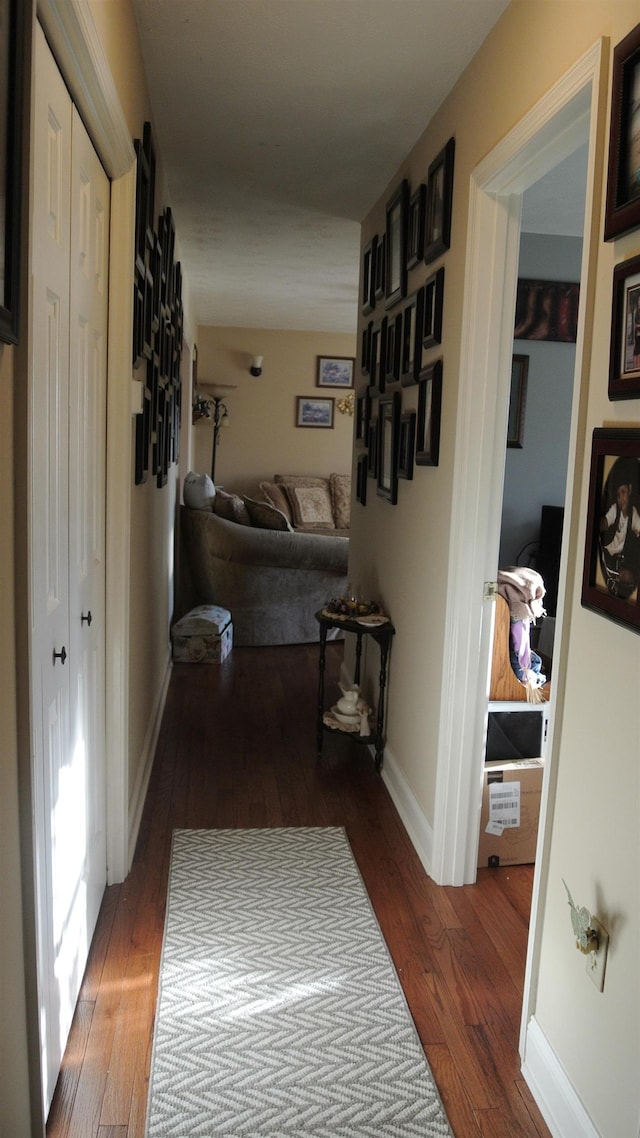 hall featuring wood-type flooring and baseboards