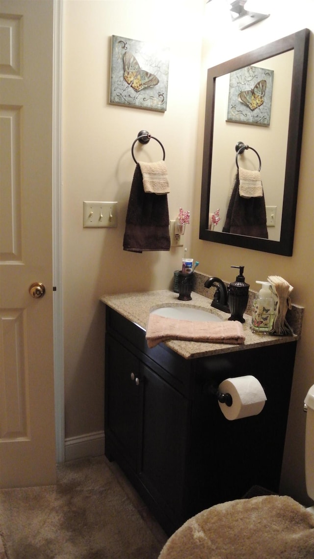 bathroom with toilet, baseboards, and vanity