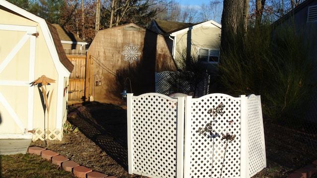 view of home's exterior with an outdoor structure, fence, a gambrel roof, a gate, and a storage unit