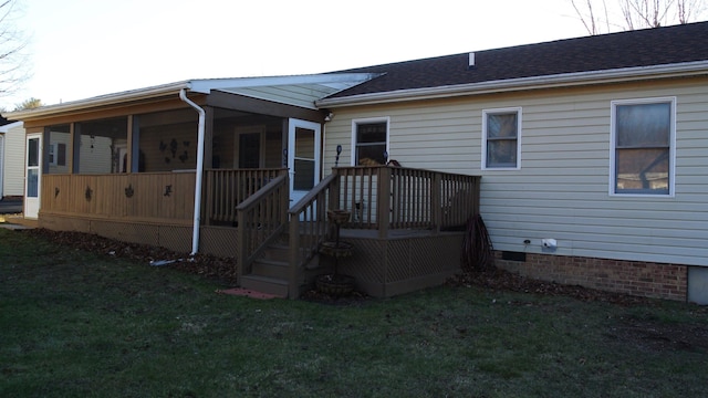 rear view of house with crawl space, a sunroom, and a lawn