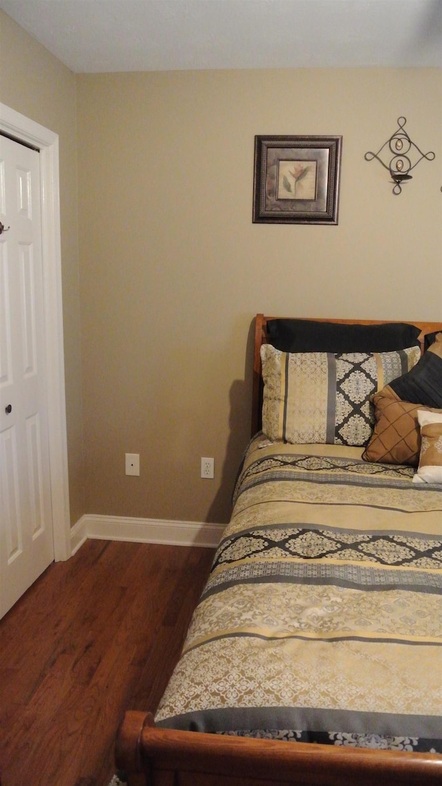 bedroom with dark wood finished floors and baseboards