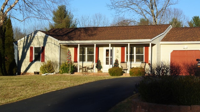 single story home featuring covered porch, a shingled roof, an attached garage, and a front yard