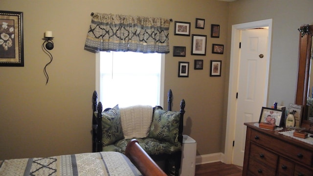 bedroom with dark wood-type flooring and baseboards