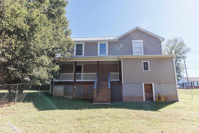 back of house featuring covered porch, fence, stairway, metal roof, and a lawn