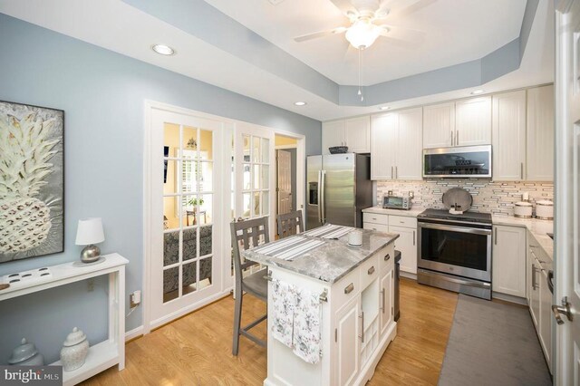 9404 Dalmahoy Ln, Fredericksburg, VA 22408 - kitchen with appliances with stainless steel finishes, decorative backsplash, ceiling fan, light wood-type flooring, and a kitchen island