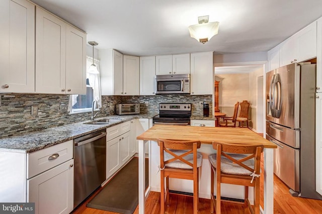  - kitchen with appliances with stainless steel finishes, light wood finished floors, tasteful backsplash, and light stone counters