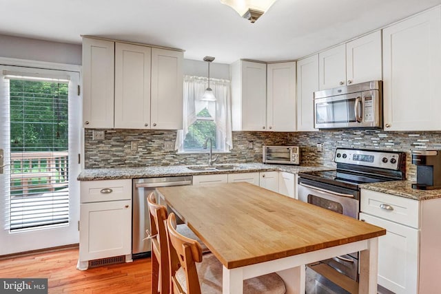  - kitchen featuring appliances with stainless steel finishes, light wood-style flooring, backsplash, and light stone countertops
