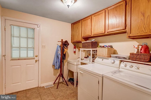  - laundry area with washing machine and clothes dryer, cabinet space, and light tile patterned floors