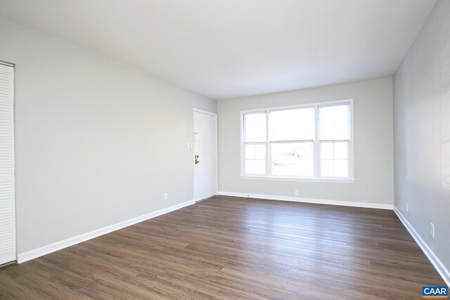 unfurnished room with dark wood-style floors and baseboards