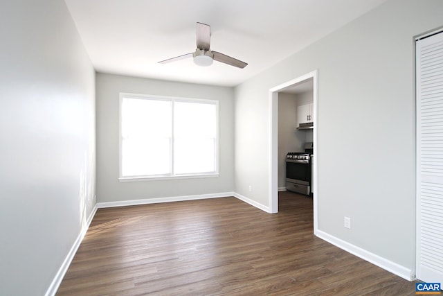 unfurnished bedroom featuring dark wood-style flooring, baseboards, a closet, and ceiling fan