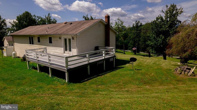  - back of property featuring a deck, a chimney, a yard, and french doors