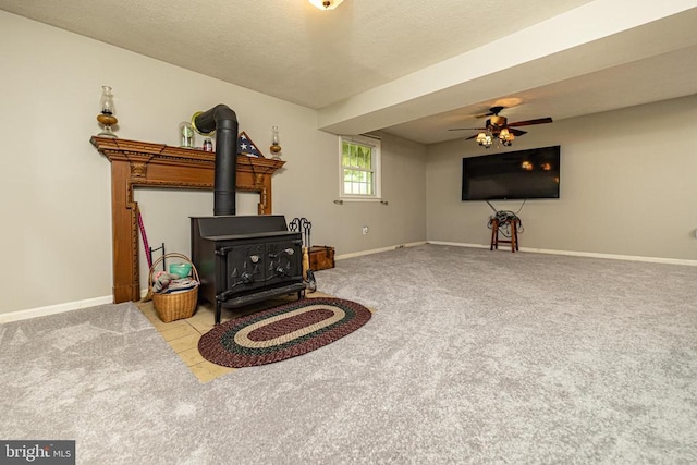  - living area featuring a wood stove, carpet, a ceiling fan, and a textured ceiling