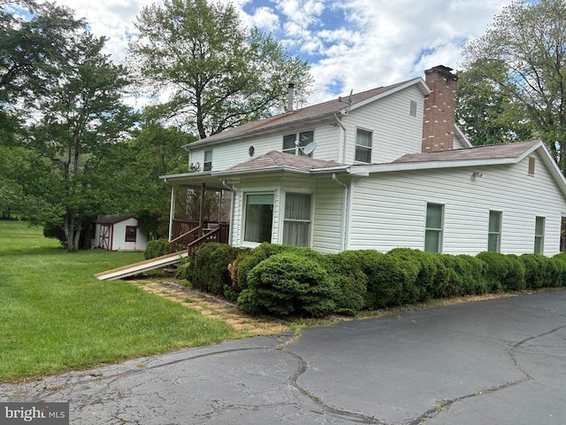  - view of side of home with a chimney and a lawn