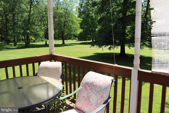  - wooden deck with a lawn, outdoor dining area, and view of scattered trees