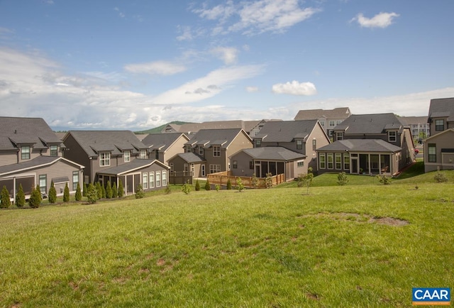 back of property featuring a residential view, a sunroom, and a lawn