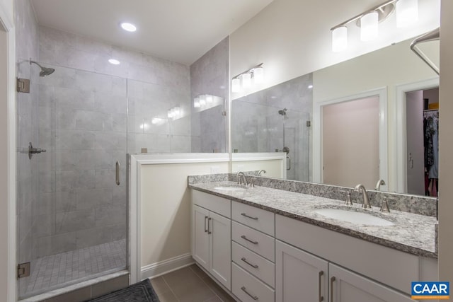 bathroom with a shower stall, double vanity, tile patterned flooring, a spacious closet, and recessed lighting