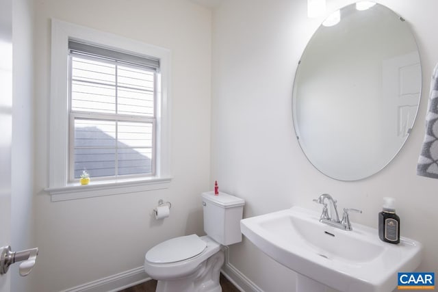 bathroom with a sink, toilet, and baseboards