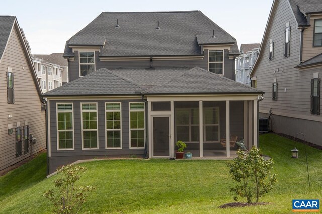 back of property featuring a shingled roof, a sunroom, and a lawn