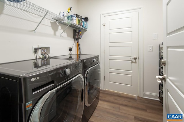 clothes washing area featuring washing machine and dryer, dark wood-style floors, and baseboards