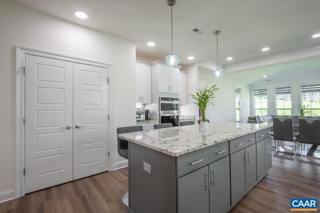 kitchen with gray cabinets, stainless steel double oven, dark wood-style flooring, a kitchen island, and white cabinetry