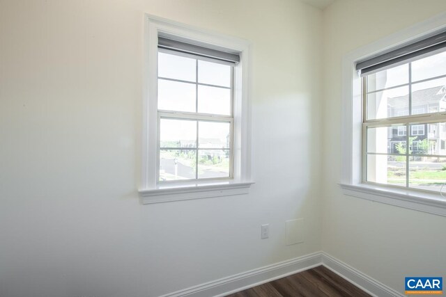 empty room with plenty of natural light, baseboards, and dark wood-style flooring