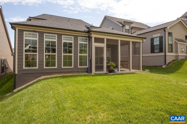 rear view of house featuring a yard, a sunroom, and a shingled roof