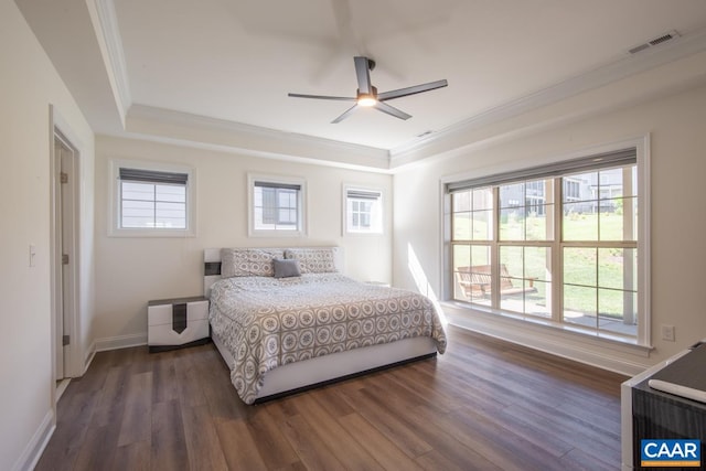 bedroom with a raised ceiling, crown molding, dark wood finished floors, baseboards, and ceiling fan