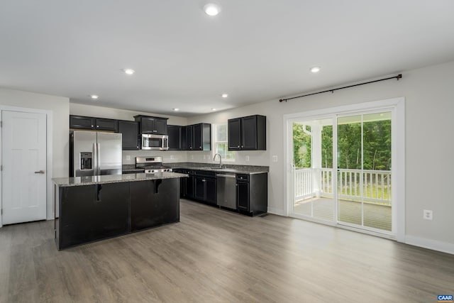 107 Archer Dr, Palmyra, VA 22963 - kitchen with appliances with stainless steel finishes, light stone counters, a breakfast bar, light wood-type flooring, and recessed lighting