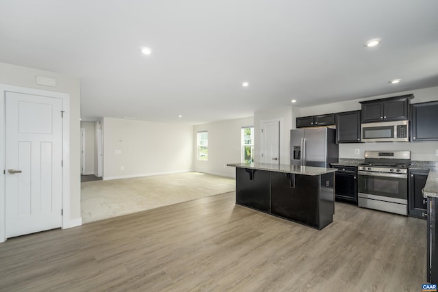 107 Archer Dr, Palmyra, VA 22963 - kitchen with appliances with stainless steel finishes, a kitchen island, open floor plan, a breakfast bar, and light wood-type flooring